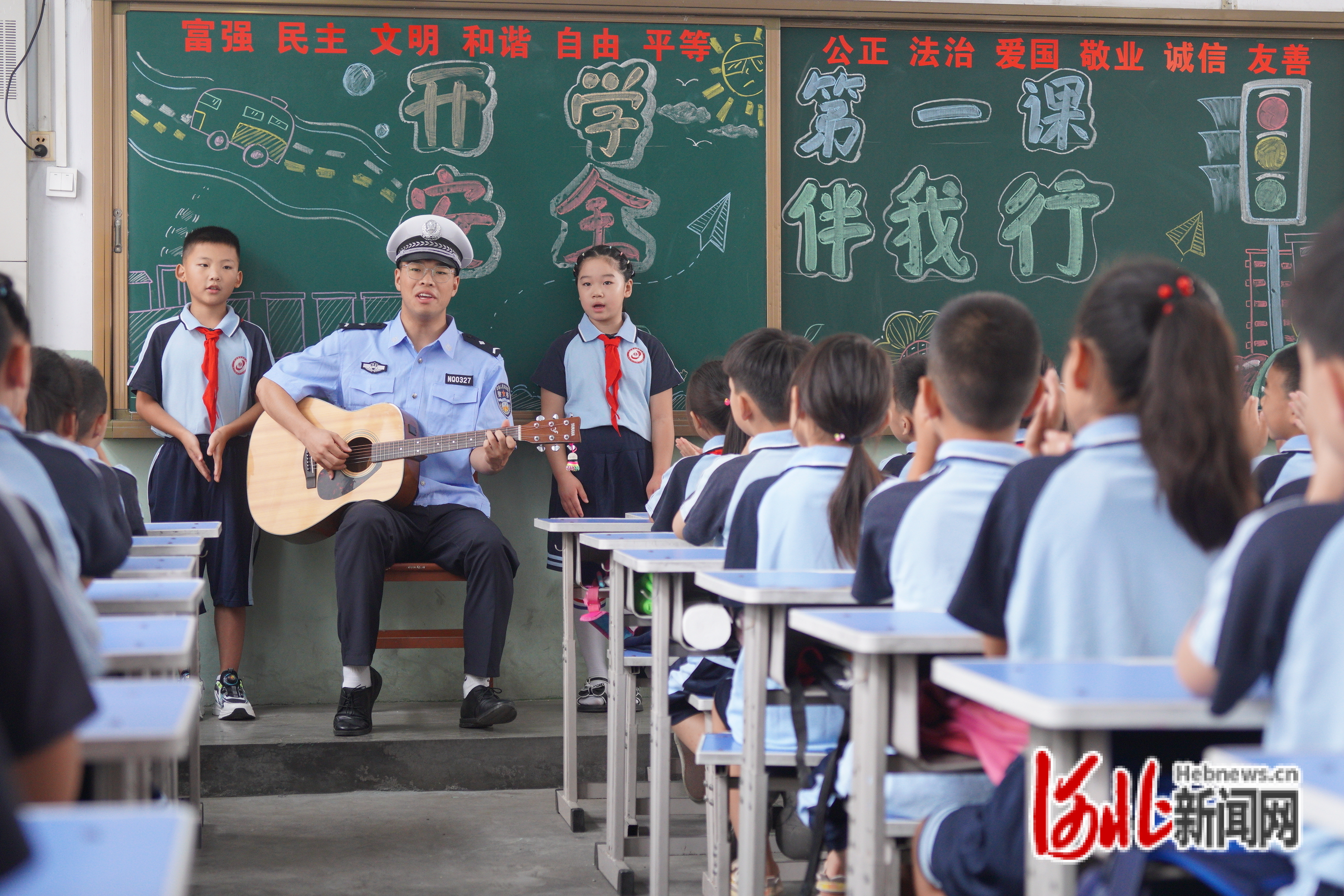 图为魏善智在为小朋友弹唱儿歌《大小朋友安全说》。
